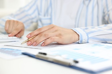 Budget planning. Woman with papers using calculator at white table, closeup