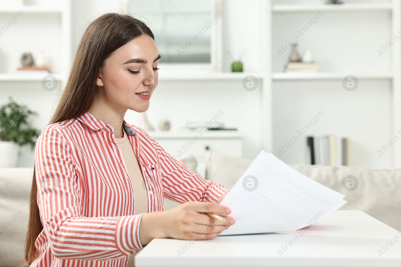 Photo of Budget planning. Beautiful young woman with papers at white table indoors