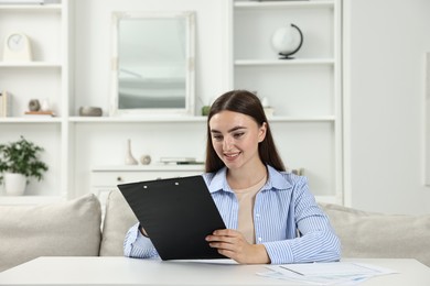 Budget planning. Beautiful young woman with papers at white table indoors