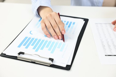 Budget planning. Woman with papers at white table, closeup