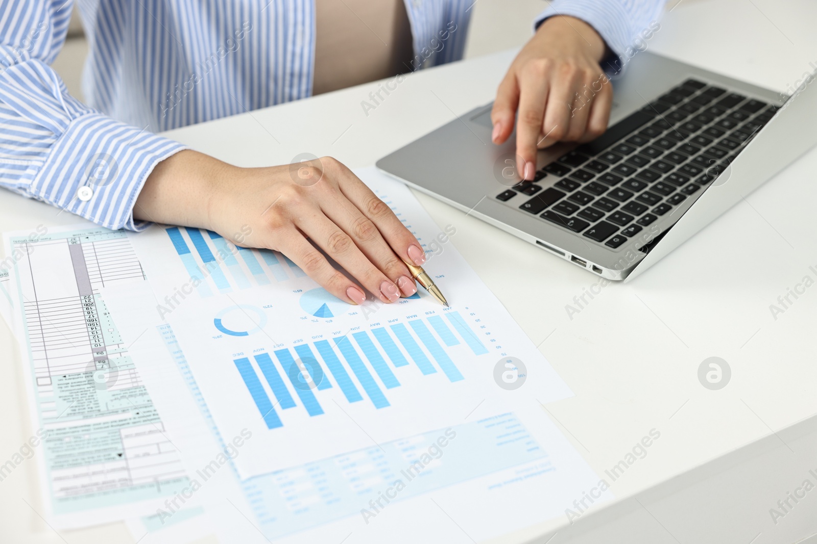 Photo of Budget planning. Woman with papers using laptop at white table, closeup