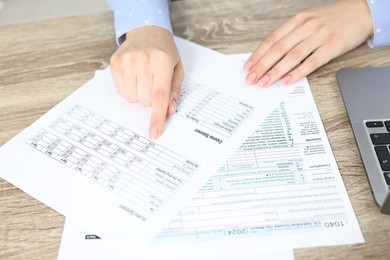 Budget planning. Woman with papers at wooden table, closeup