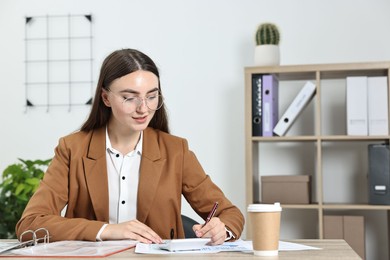 Budget planning. Beautiful young woman with papers and calculator at wooden table in office