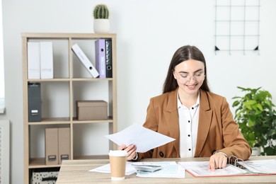 Photo of Budget planning. Beautiful young woman with papers and calculator at wooden table in office