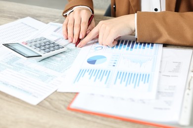 Budget planning. Woman with papers and calculator at wooden table, closeup