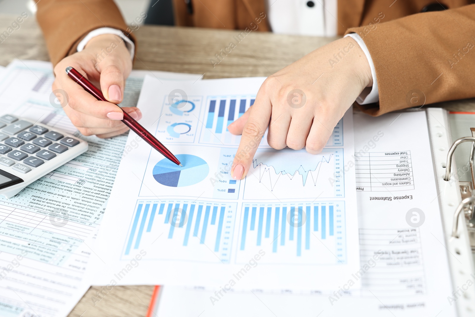 Photo of Budget planning. Woman with papers and calculator at wooden table, closeup