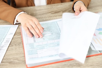 Photo of Budget planning. Woman with papers at wooden table, closeup