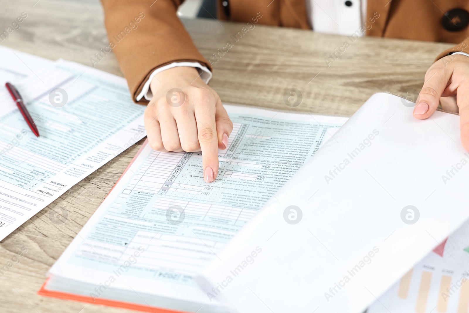 Photo of Budget planning. Woman with papers at wooden table, closeup