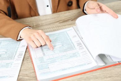 Photo of Budget planning. Woman with papers at wooden table, closeup