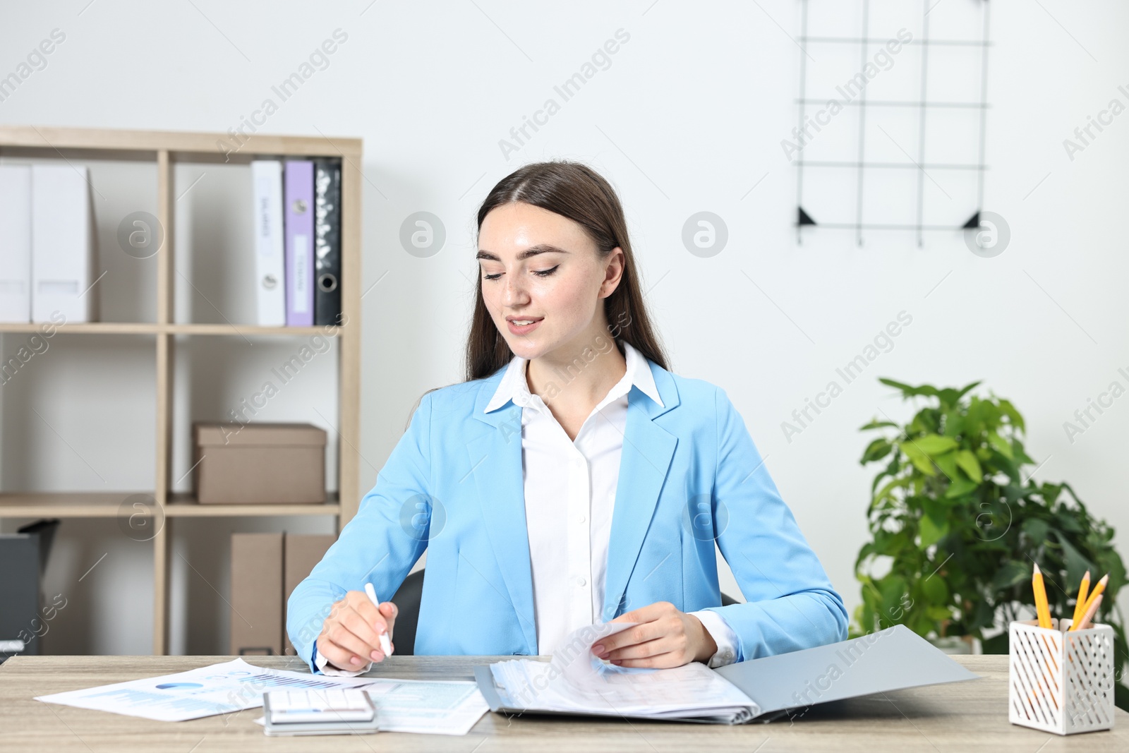 Photo of Budget planning. Beautiful young woman with papers and calculator at wooden table in office