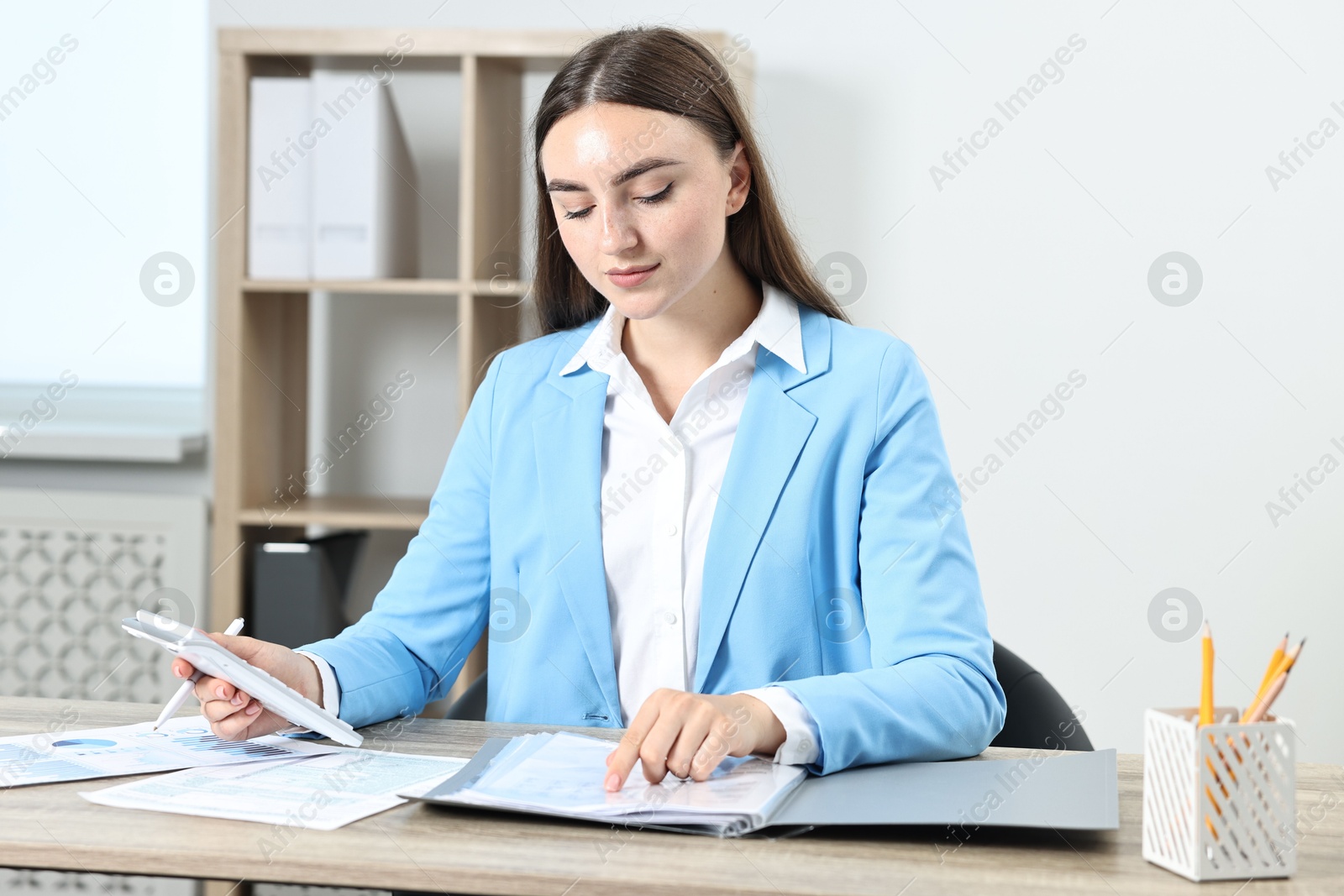 Photo of Budget planning. Beautiful young woman with papers and calculator at wooden table in office