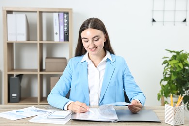 Budget planning. Beautiful young woman with papers and calculator at wooden table in office