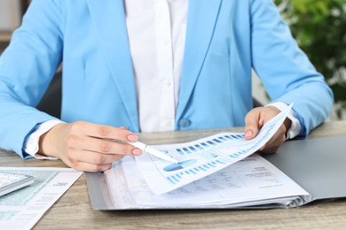 Photo of Budget planning. Woman with papers at wooden table, closeup