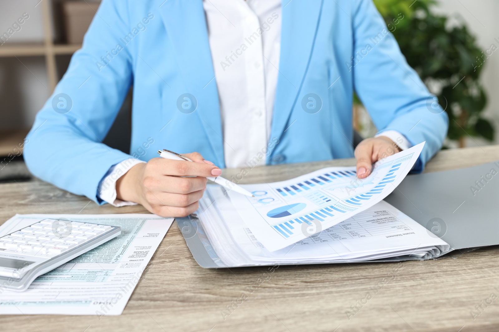 Photo of Budget planning. Woman with papers and calculator at wooden table, closeup