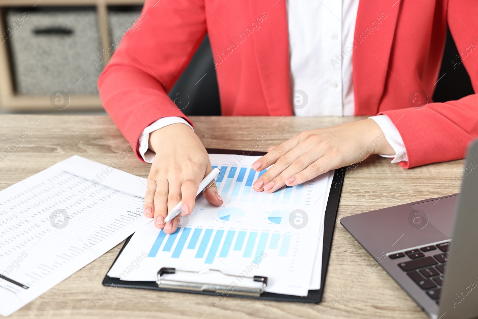 Photo of Budget planning. Woman with papers and laptop at wooden table, closeup