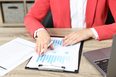 Photo of Budget planning. Woman with papers and laptop at wooden table, closeup