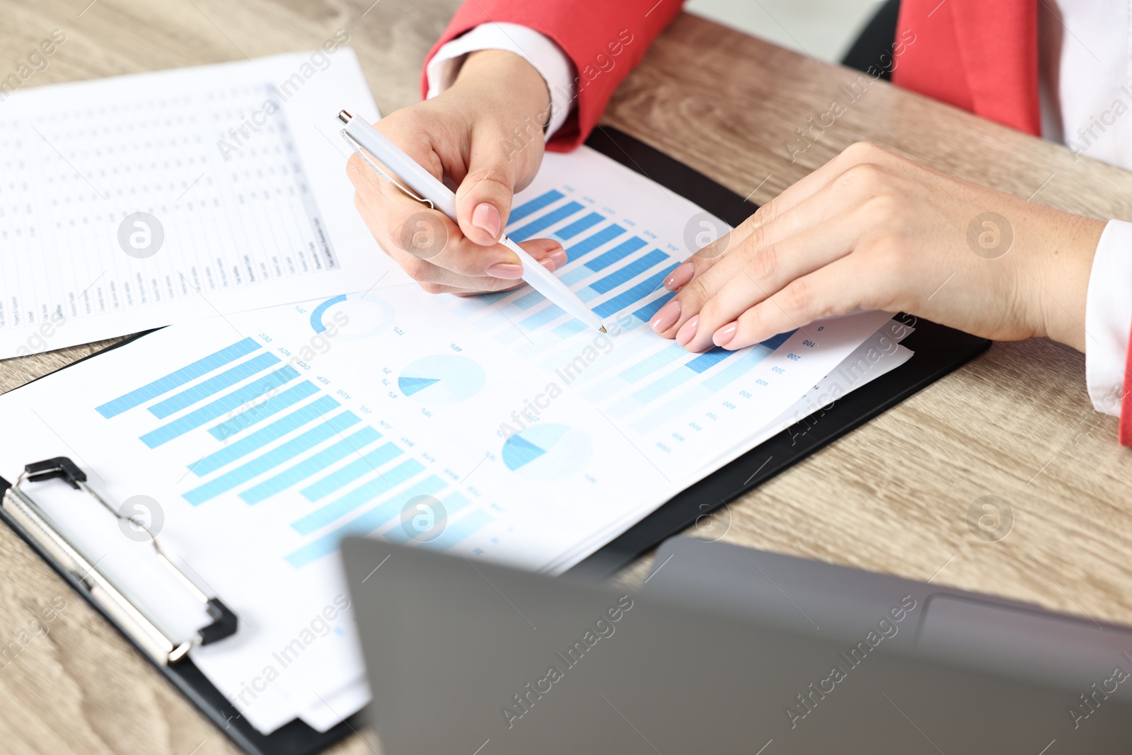 Photo of Budget planning. Woman with papers and laptop at wooden table, closeup