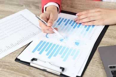 Photo of Budget planning. Woman with papers at wooden table, closeup