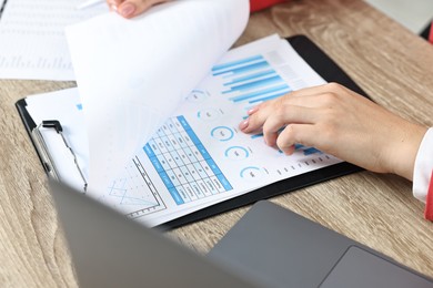 Budget planning. Woman with papers at wooden table, closeup