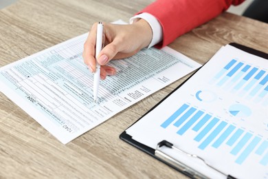 Budget planning. Woman with papers at wooden table, closeup