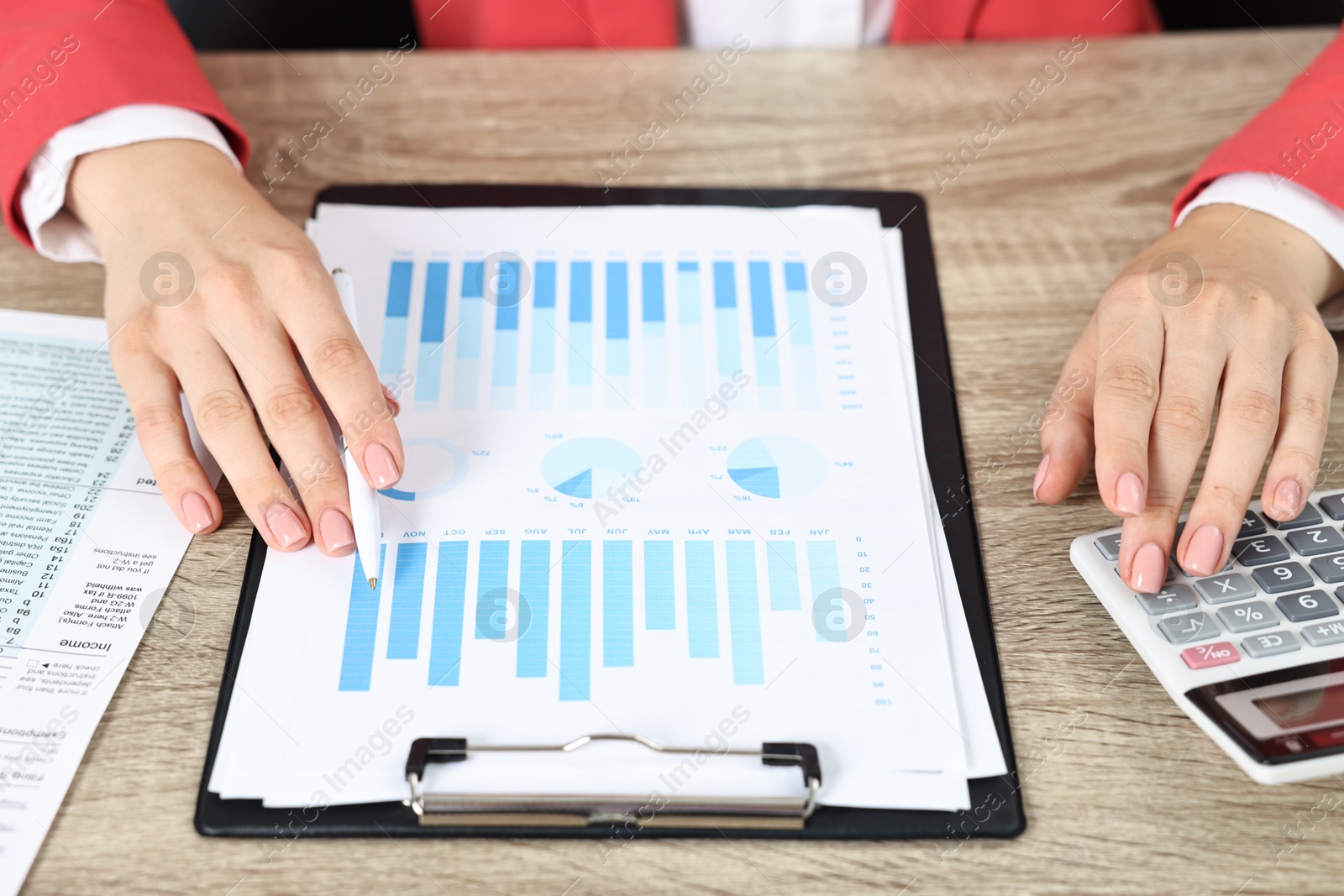 Photo of Budget planning. Woman with papers and calculator at wooden table, closeup