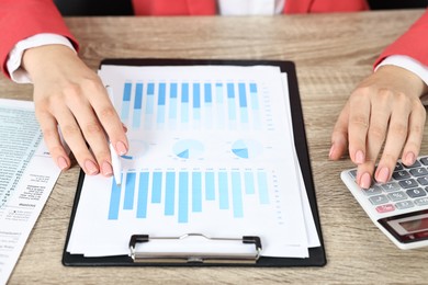 Budget planning. Woman with papers and calculator at wooden table, closeup