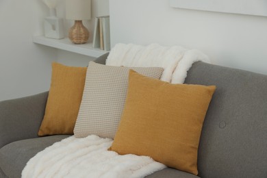 Photo of Different soft pillows and blanket on sofa in room