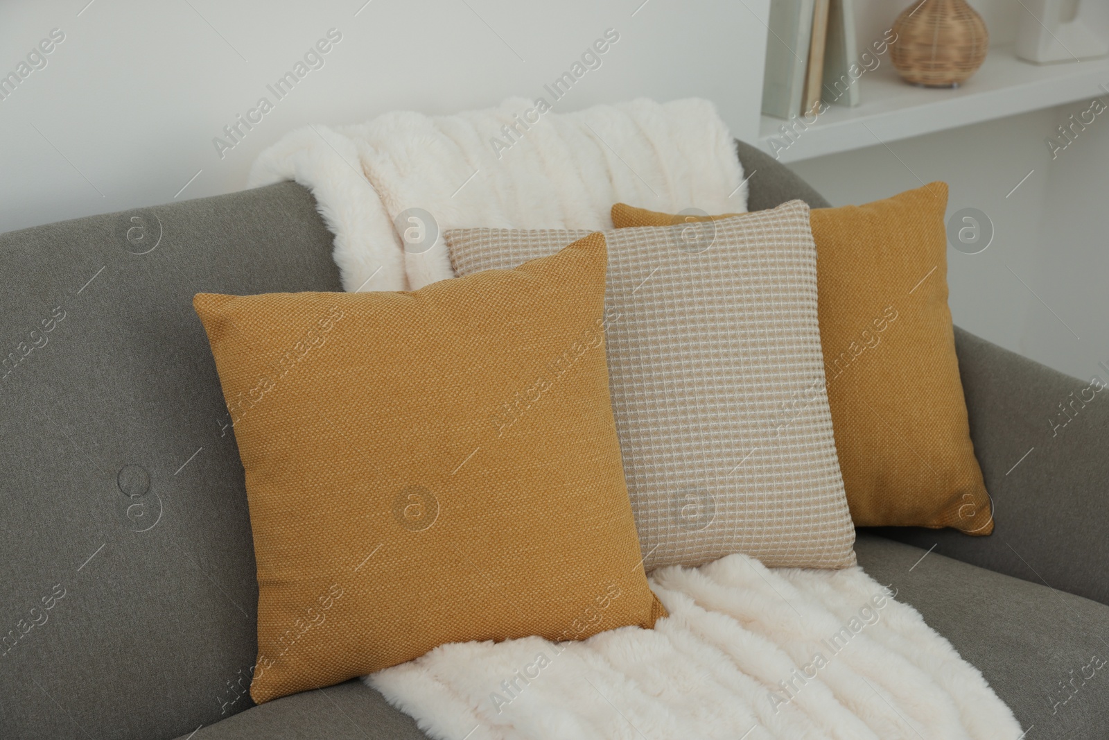 Photo of Different soft pillows and blanket on sofa in room