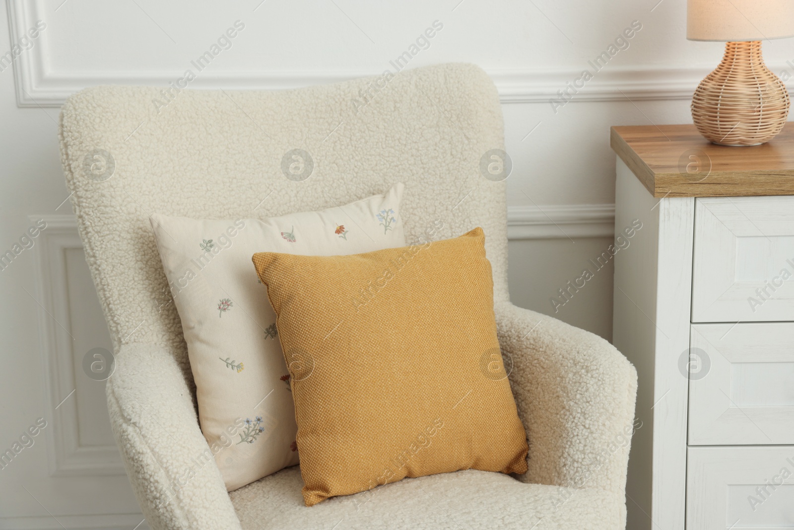 Photo of Two soft pillows on light armchair indoors