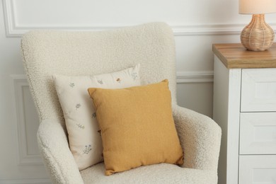 Photo of Two soft pillows on light armchair indoors