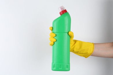 Woman holding toilet cleaner in bottle on light background, closeup. Space for text