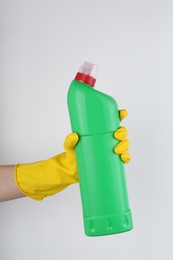 Photo of Woman holding toilet cleaner in bottle on light background, closeup