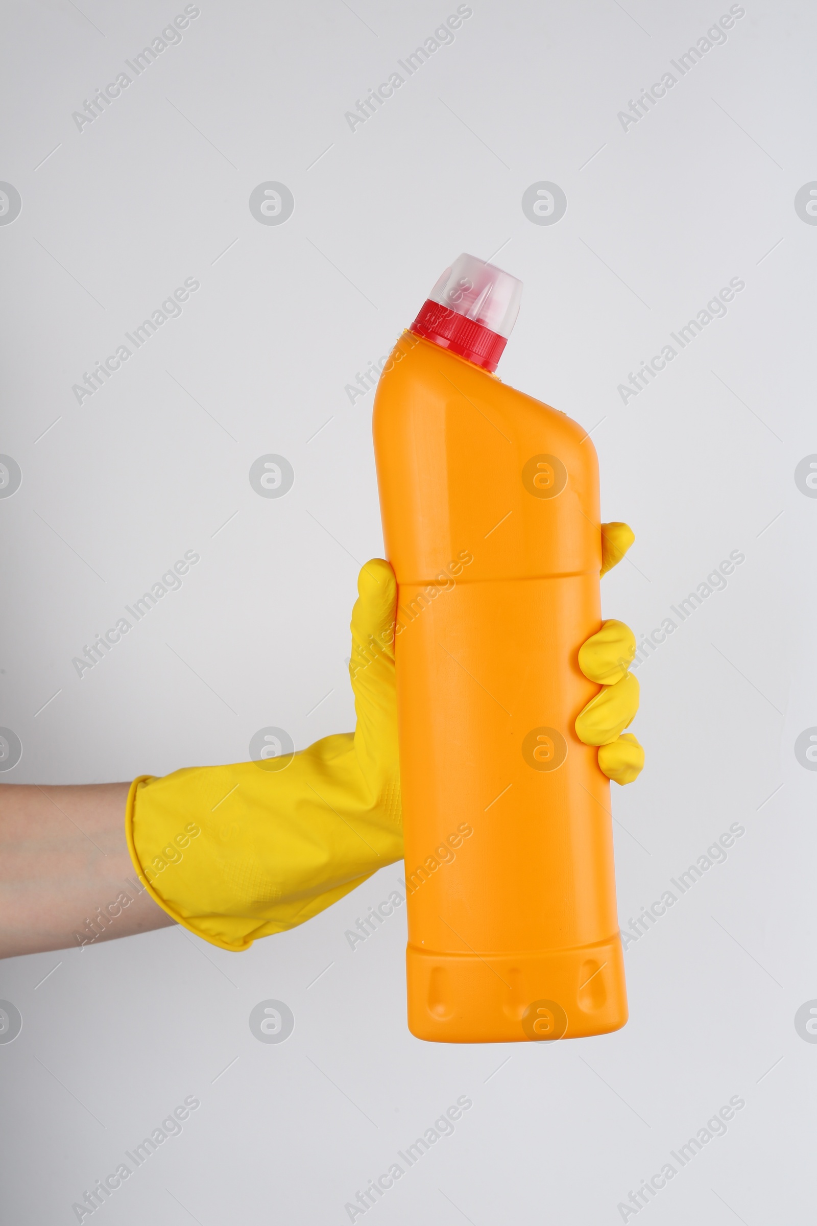 Photo of Woman holding toilet cleaner in bottle on light background, closeup