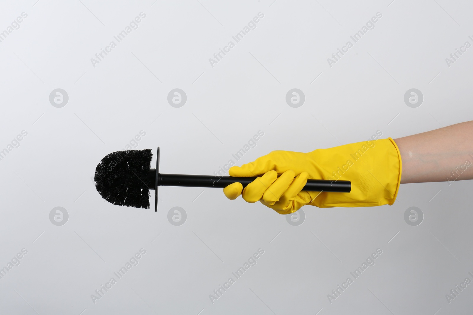 Photo of Woman holding black toilet brush on light background, closeup. Cleaning tool