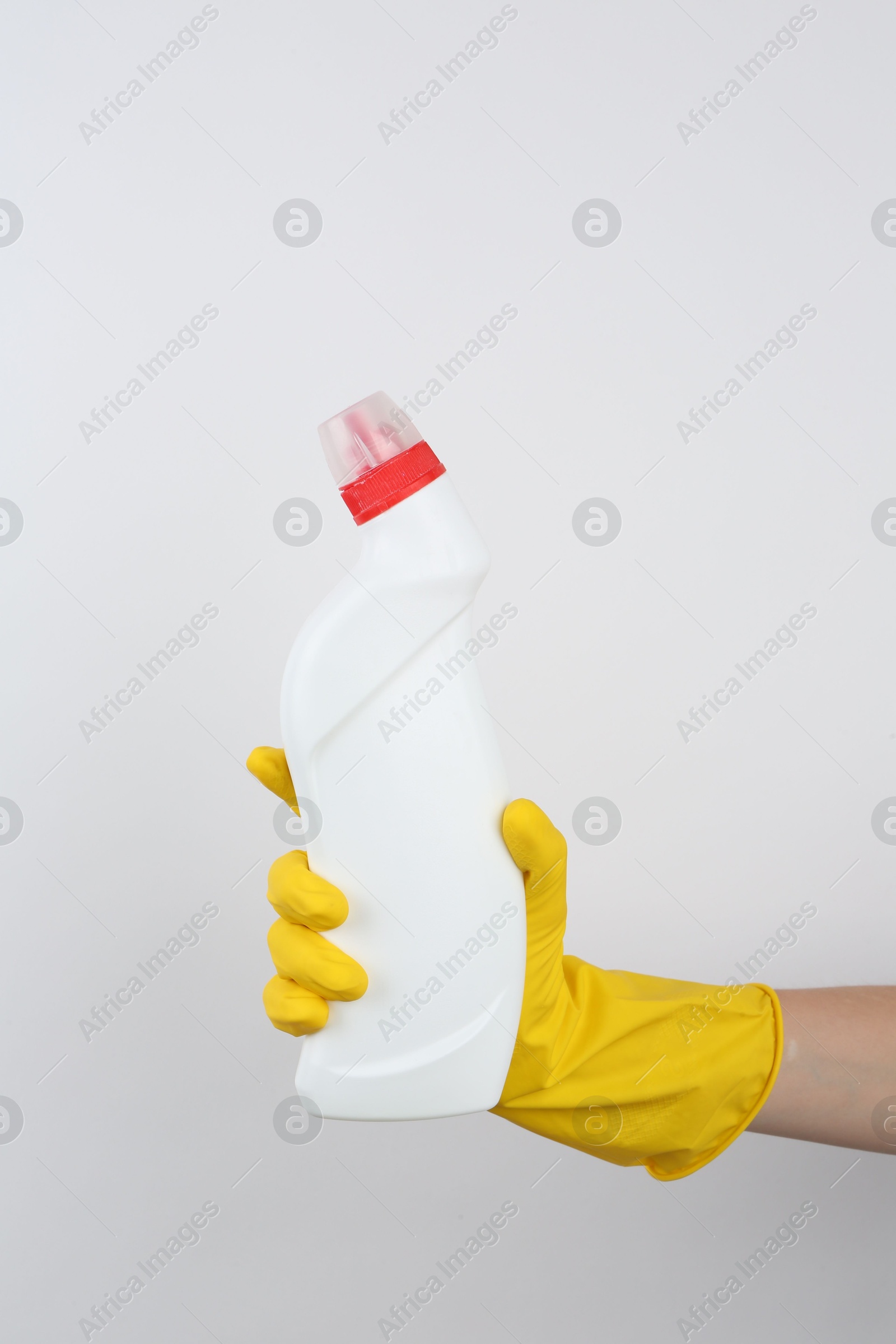 Photo of Woman holding toilet cleaner in bottle on light background, closeup