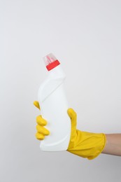 Photo of Woman holding toilet cleaner in bottle on light background, closeup