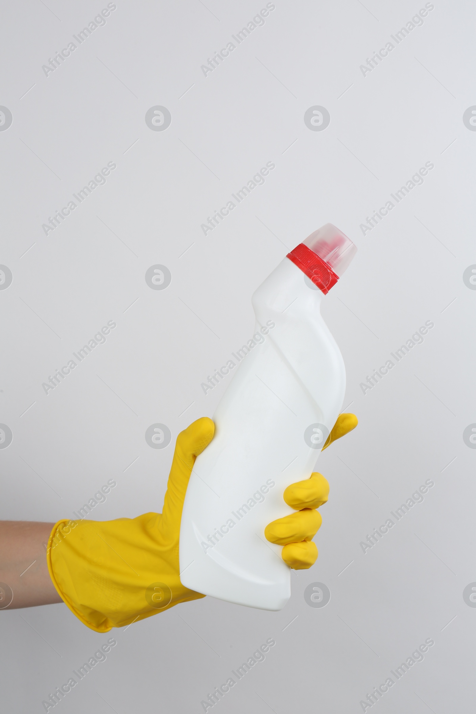 Photo of Woman holding toilet cleaner in bottle on light background, closeup