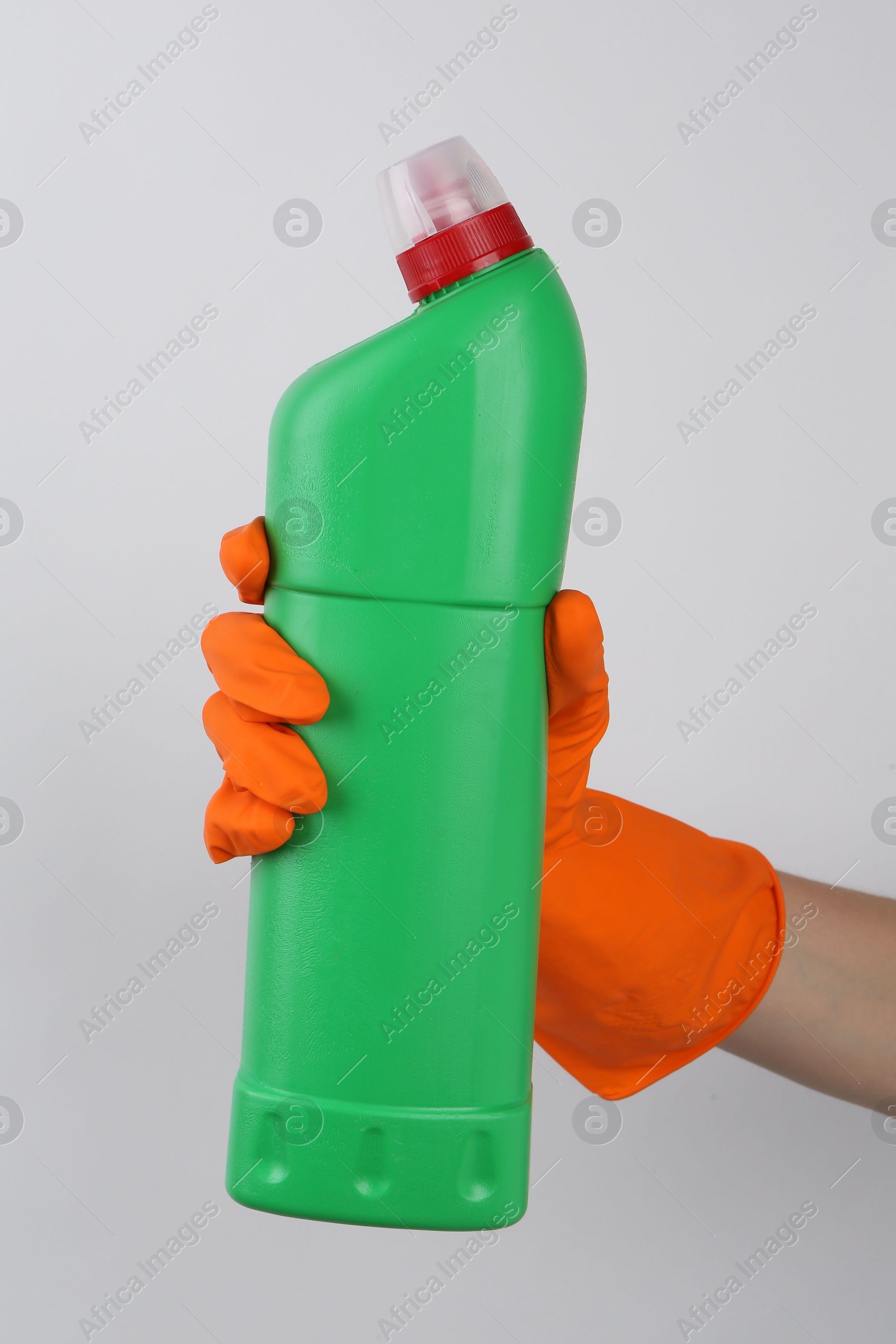 Photo of Woman holding toilet cleaner in bottle on light background, closeup