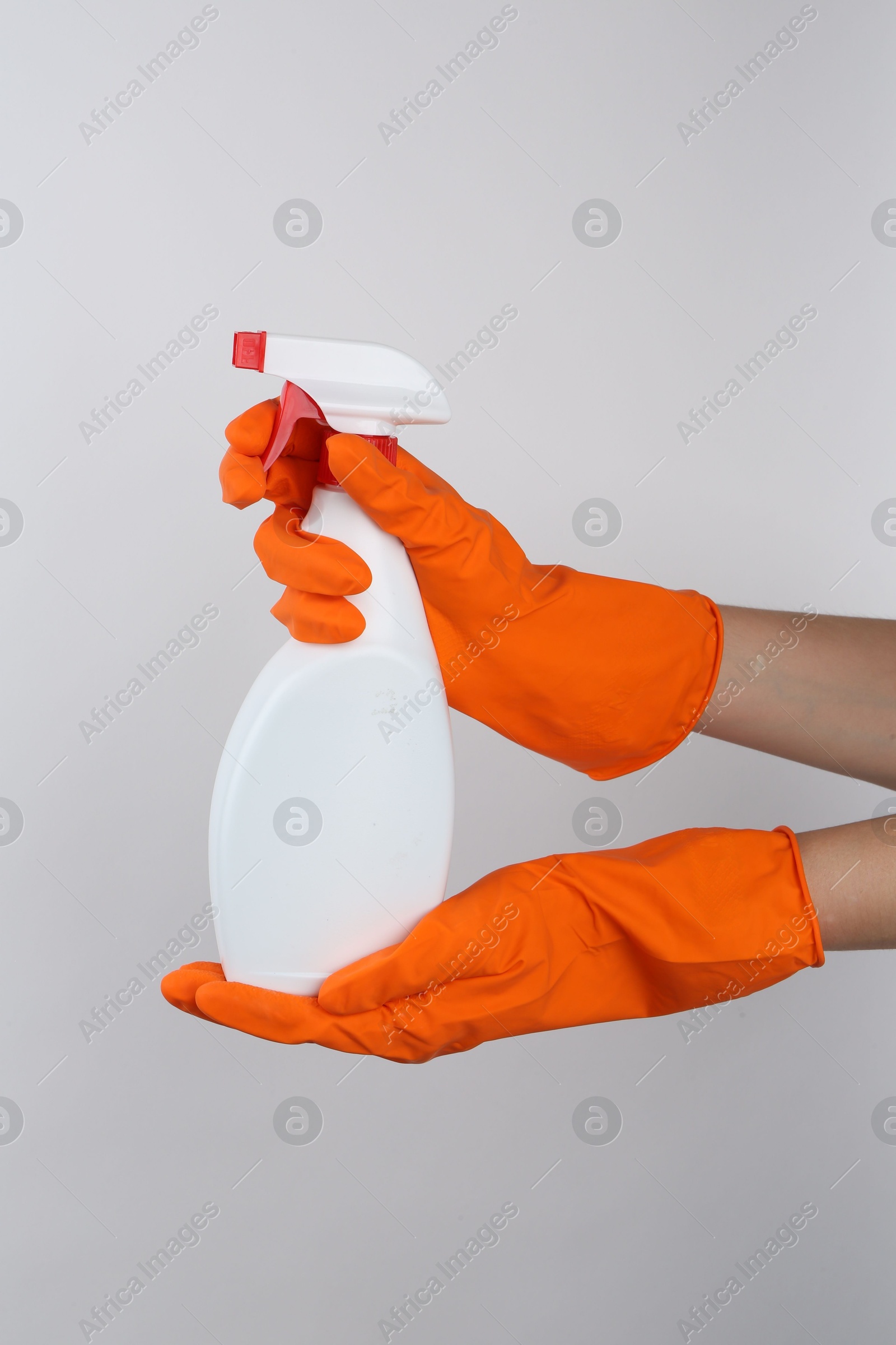 Photo of Woman holding toilet cleaner in spray bottle on light background, closeup