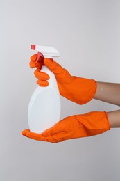 Photo of Woman holding toilet cleaner in spray bottle on light background, closeup