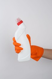 Photo of Woman holding toilet cleaner in bottle on light background, closeup