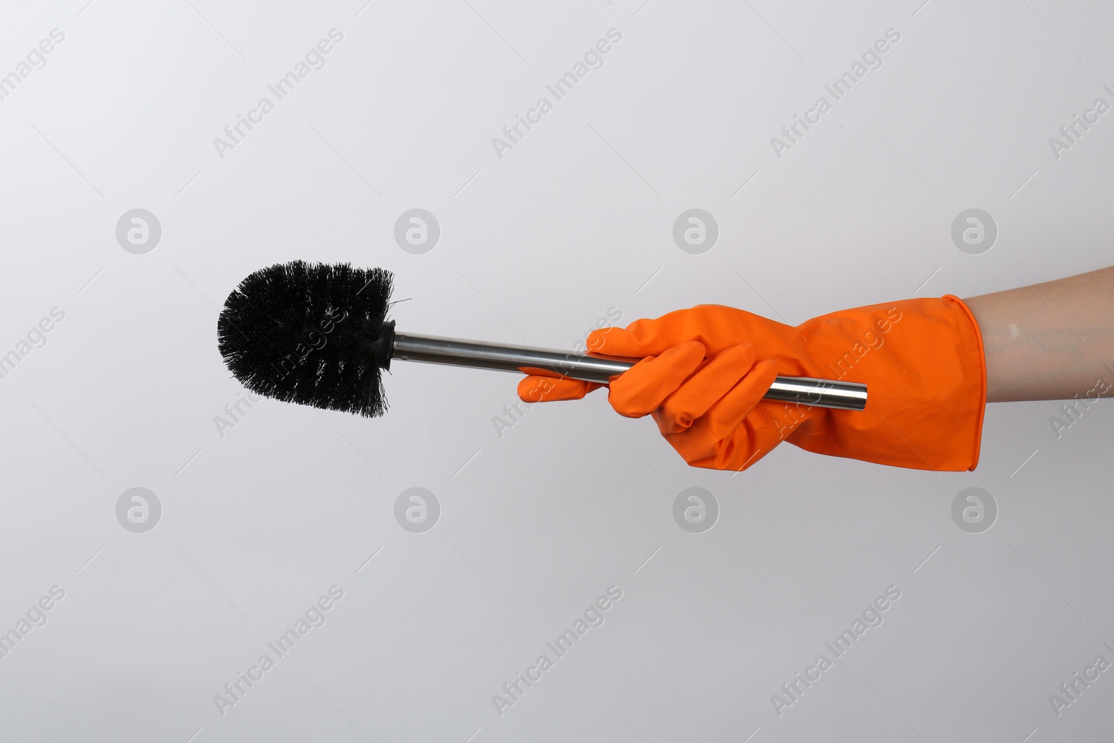 Photo of Woman holding black toilet brush on light background, closeup. Cleaning tool