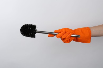 Photo of Woman holding black toilet brush on light background, closeup. Cleaning tool