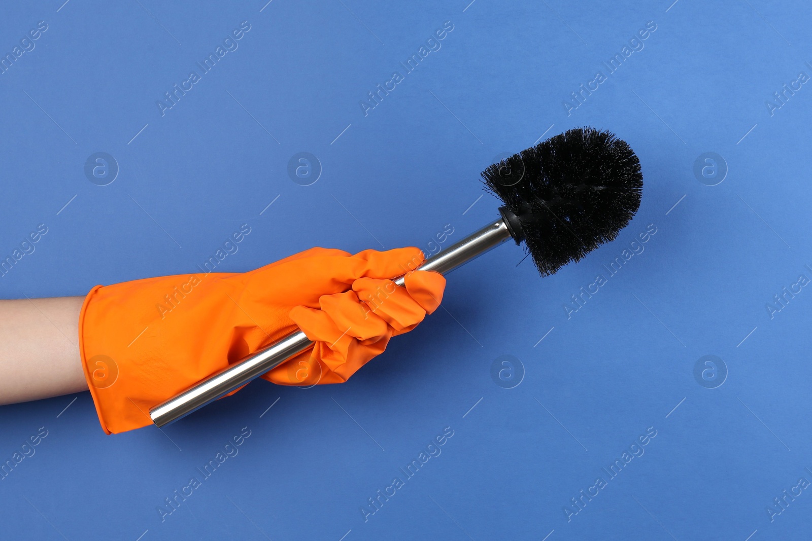 Photo of Woman holding black toilet brush on blue background, closeup. Cleaning tool