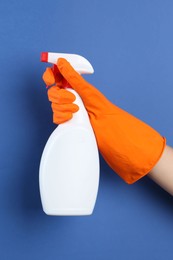 Photo of Woman holding toilet cleaner in spray bottle on blue background, closeup