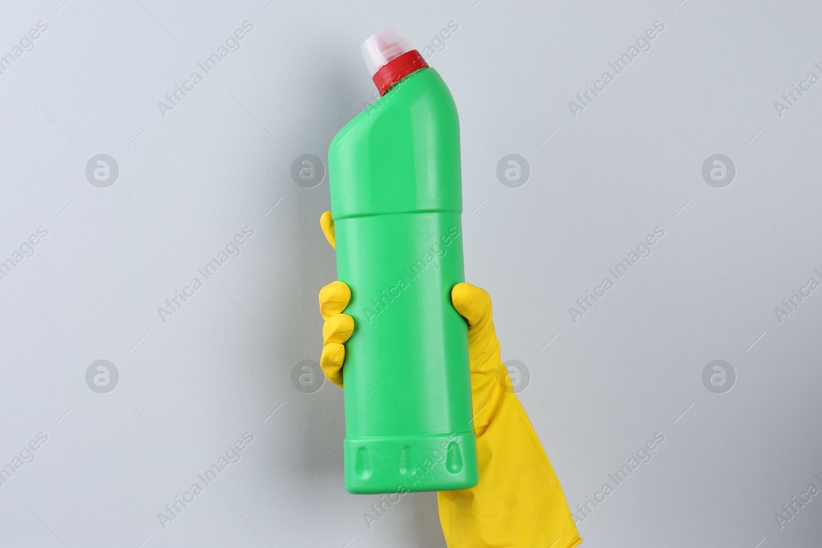 Photo of Woman holding toilet cleaner in bottle on light background, closeup