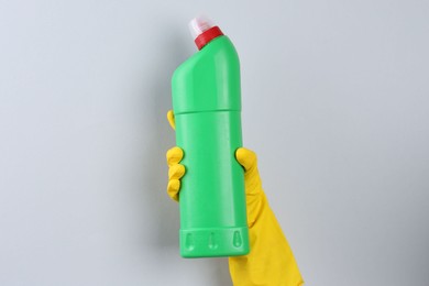 Photo of Woman holding toilet cleaner in bottle on light background, closeup