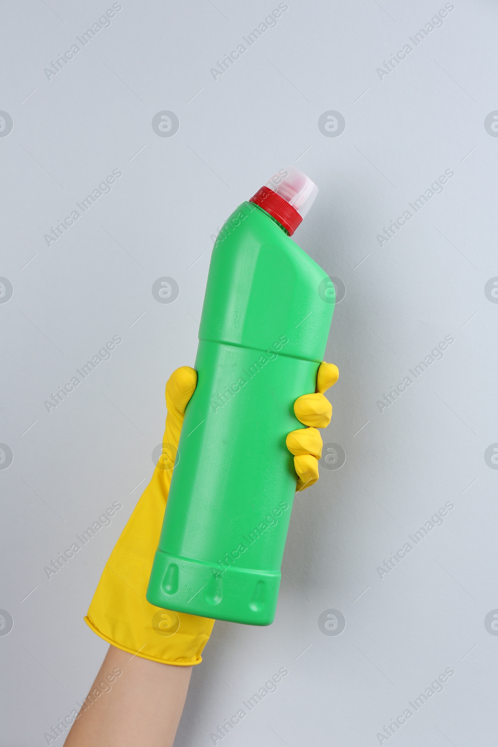 Photo of Woman holding toilet cleaner in bottle on light background, closeup