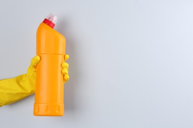 Photo of Woman holding toilet cleaner in bottle on light background, closeup. Space for text