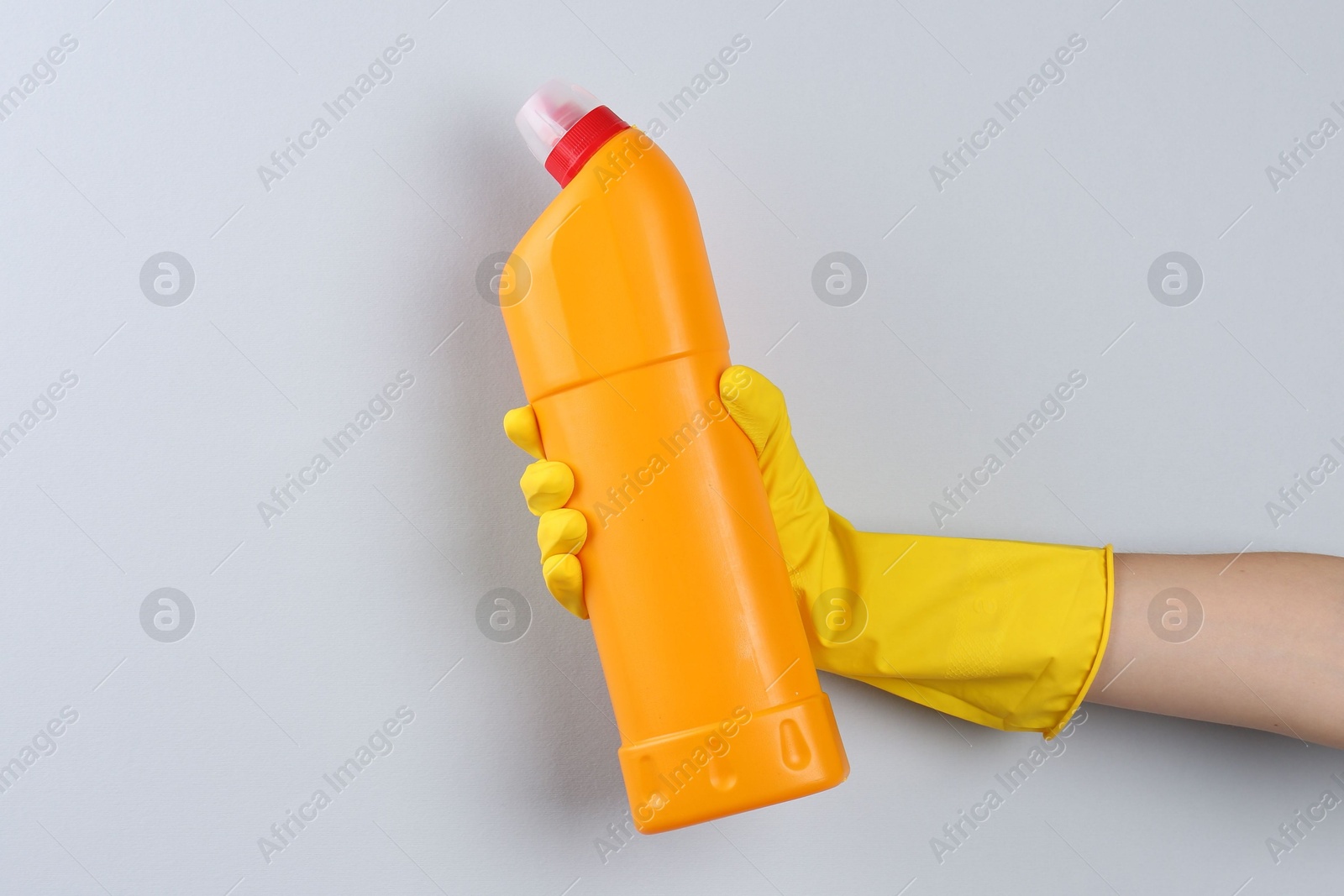 Photo of Woman holding toilet cleaner in bottle on light background, closeup